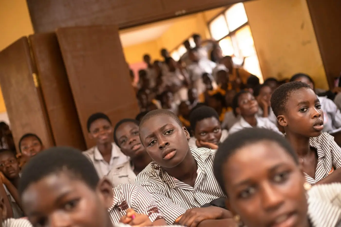 A crowded classroom of secondary-school students listening intently